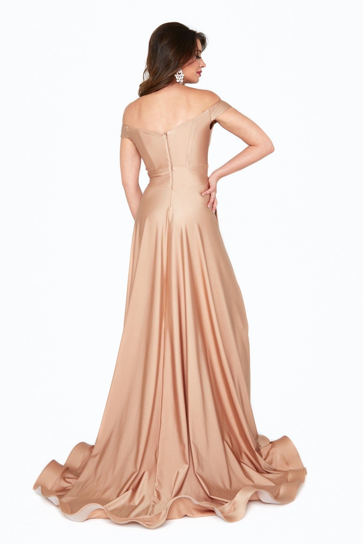 A woman stands with her back to the camera in a champagne Atria 6531H long A-line prom dress with pockets and a flared skirt, set against a plain white background.